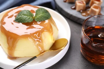 Delicious pudding with caramel sauce and mint served on gray table, closeup