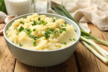 Delicious mashed potato with green onions on wooden table, closeup