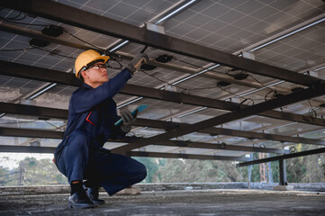 A solar panel maintenance technician is checking the wiring that is being installed to the solar...