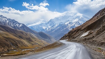 A breathtaking high-altitude road with a panoramic view of snow-capped mountains and deep valleys.