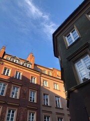 Fototapeta premium Charming European old town buildings bathed in warm golden-hour light. The colorful facades, intricate architectural details, and deep blue sky create a picturesque and inviting urban scene