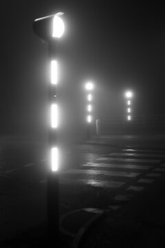Belisha beacons on a road crossing, pedestrian crossing or crosswalk on a foggy night
