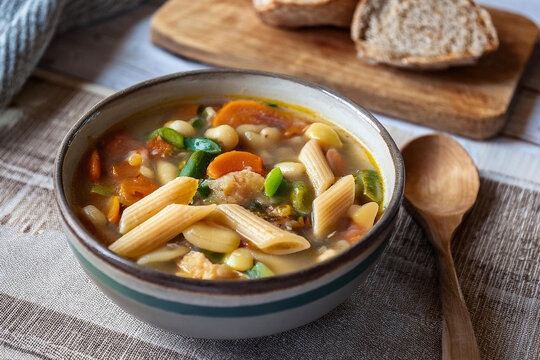 Sopa de verduras italiana en cuenco de cer&aacute;mica, con caldo dorado, zanahoria, calabac&iacute;n, jud&iacute;as y pasta