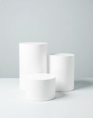 three white cylindrical display platforms on light gray surface