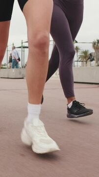 Vertical video, Group of diverse female friends jogging together by the sea. Fitness, friendship, and coastal workout vibes.