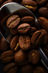 Naklejka premium Coffee beans on a chrome plated spoon. Macrophotograph. Morning mood. First person image. Textured background. Postcard. Cover. Wallpaper. Picture