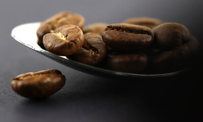 Coffee beans on a chrome plated spoon. Macrophotograph. Morning mood. First person image. Textured background. Postcard. Cover. Wallpaper. Picture