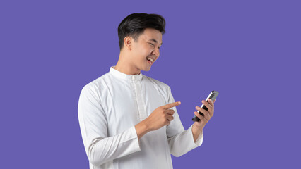 Cheerful young Asian Muslim man making a video call on mobile phone, isolated on white background.
Ramadan and Eid celebrations on purple background