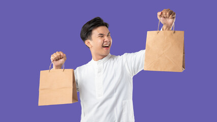 A man holds a brown paper bag and smiles. Ramadan and Eid celebrations on purple background