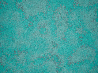 A close-up of cement with a turquoise finish, accented with grey spots and rough texture.