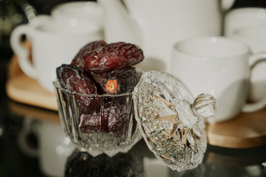 dates kept in a glass dish with a coffee mug in the background