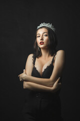 Fototapeta premium A woman with dark hair and red lipstick. She is wearing black lace lingerie and black pants.