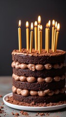 Tiered chocolate birthday cake with gold birthday candles