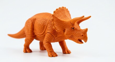 Fototapeta premium Intricate orange Triceratops toy stands proudly against bright white background. AI Generated