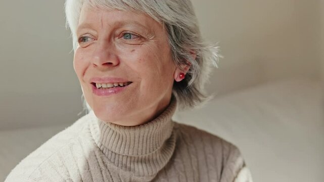 Close-up of a cheerful senior woman with gray hair, expressing happiness and contentment in her cozy home.