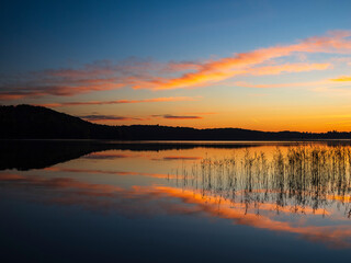 Serene autumn sunset over a tranquil lake with reflecting reeds in Sweden