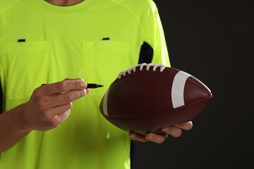 Professional player signing autograph on American football ball black background, closeup
