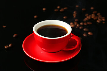Red cup with coffee and roasted beans on black background