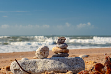 Tower of Pebbles on a Large Stone against the Ocean Beach Background Sunny Day