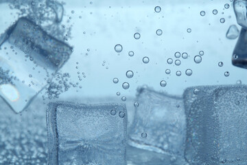 Refreshing soda water with ice cubes as background, closeup