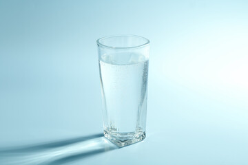 Soda water in glass on light blue background
