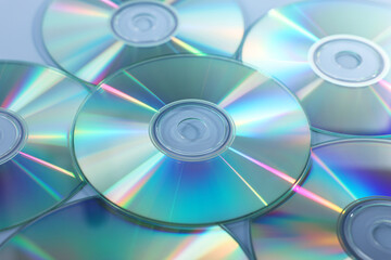 Many shiny compact discs on dusty blue background, closeup