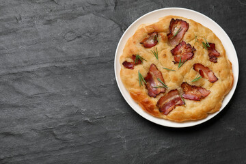 Delicious focaccia bread with bacon and rosemary on black table, top view. Space for text