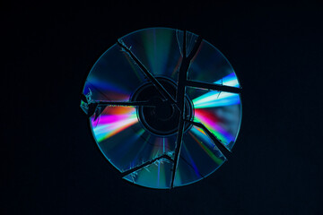Broken compact disc on black background, top view