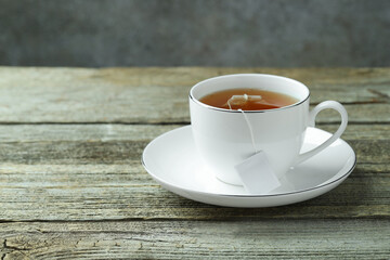 Tea bag in cup with hot drink on wooden table. Space for text
