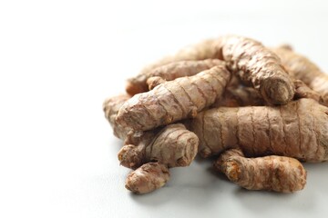 Pile of raw turmeric roots on white marble table, closeup. Space for text