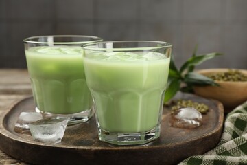Fresh mung bean juice with ice in glasses on wooden table, closeup