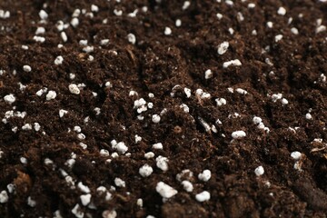 Fresh soil with fertilizer as background, closeup