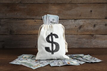 Burlap sack with dollar banknotes on wooden table