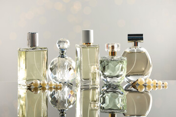 Different luxury perfumes on glass surface. Bokeh effect