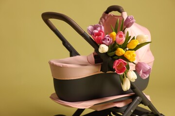 Stylish doll stroller and tulips on olive background. Kid's toy