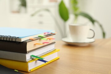 Stack of books and notebook with colorful bookmarks on wooden table, closeup. Space for text
