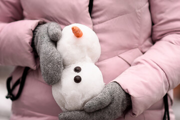 a small snowman made of snow in women's hands