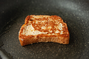 Making French toast, close-up of a nicely golden piece of French toast cooking in a frying pan, traditional breakfast preparation