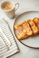 Traditional homemade breakfast - a cup of coffee and French toast with honey,   bread soaked in eggs and milk, served on a white plate and shot in bright morning light with copy space on left side