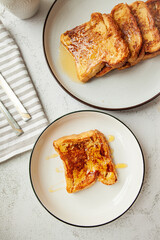 Traditional homemade breakfast - a cup of coffee and French toast with honey,   bread soaked in eggs and milk, served on a white plate and shot in bright morning light with copy space on left side