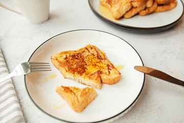 Traditional homemade breakfast - a cup of coffee and French toast with honey, served on a white plate and shot in bright morning light 