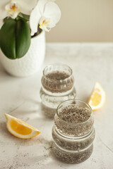 Two glasses of healthy drink to start the day - chia water with lemon on white background, great for hydration, digestion and detox, shot in bright morning light