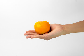 A hand holding a fresh, whole orange, showcasing its bright color and smooth texture. Ideal for healthy snacking or adding zest to various dishes.