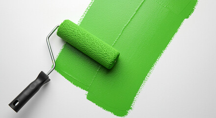 Obraz premium Green paint roller applying a fresh coat on a white surface