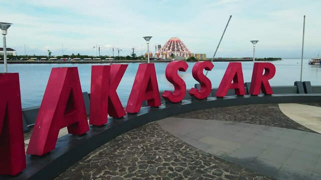 Aerial drone view of 99 Kubah and Losari Beach moving forward with the Makassar sign in the foreground