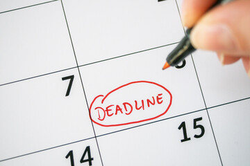 Close up of Deadline written on date with red marker. Cropped image of hand marking deadline date on calendar