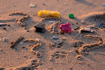 Plastic trash on the beach. Pollution of the environment with plastic. Ocean beach polluted with waste. A question mark drawn in the sand. Close-up photo.