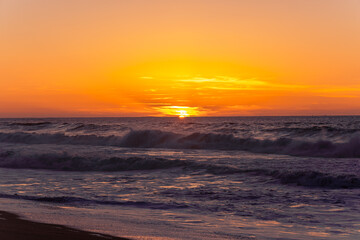 The most beautiful sunset on the ocean coast. Golden hour on the beach. The sky in bright colours of the sunset and the calm ocean