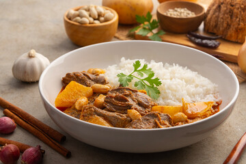 Massaman Curry with beef and cooked rice in white plate.Cooked beef meat and potatoes groundnut with massaman curry paste in coconut milk.asian food.