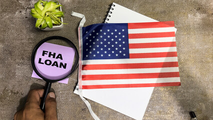 Concept of FHA Loan write on sticky notes and Flag of the United States isolated on Wooden Table.